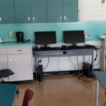 picture of tables, computers, and whiteboards in a classroom